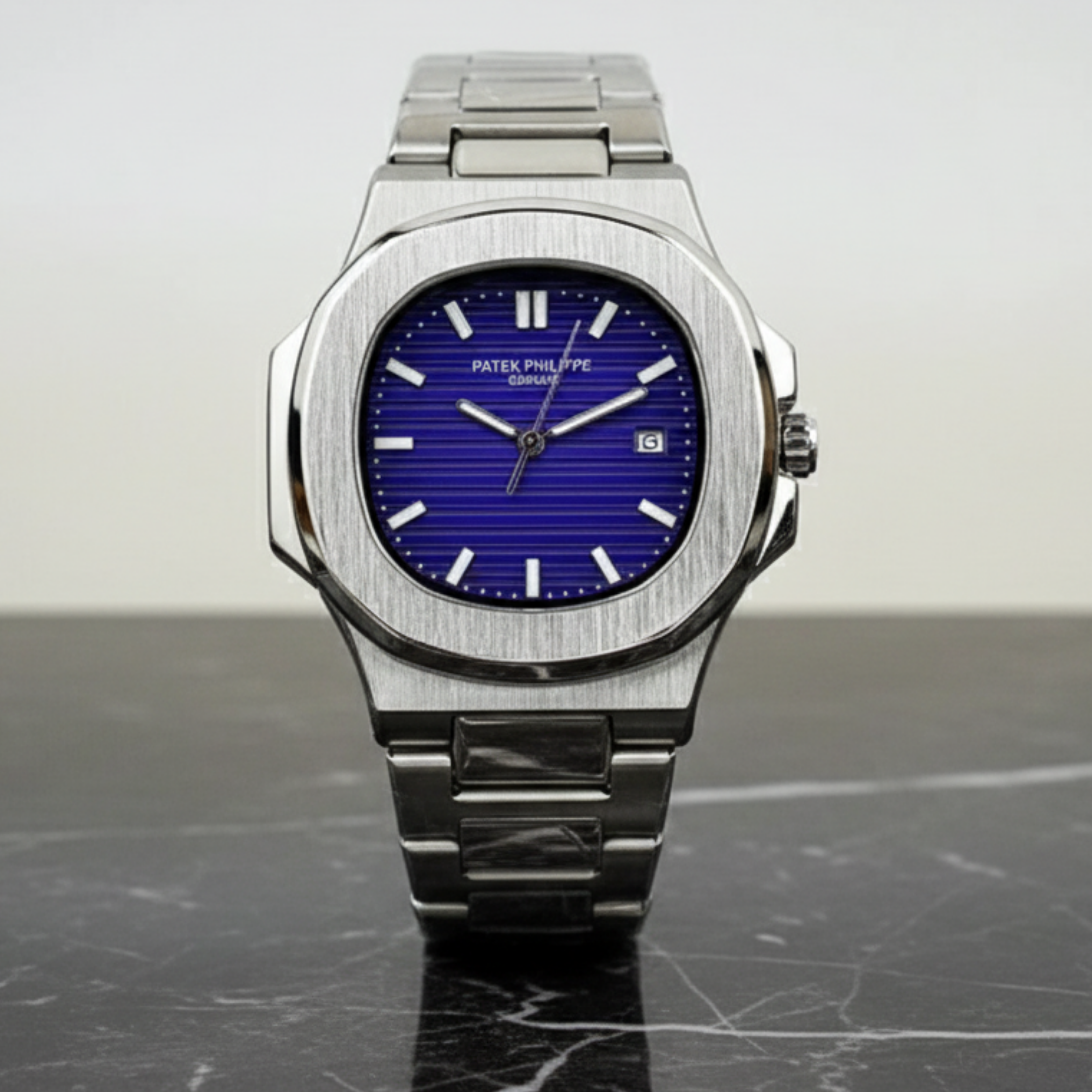 Silver Patek Philippe watch with a blue face on a gray surface